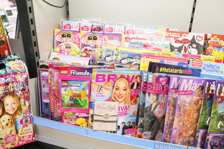 Ein Zeitschriftenregal voller bunter Kinder- und Jugendmagazine, darunter Comics und Modehefte.