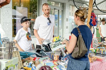 Lehrgang im Umgang mit Geld: Patrick Lang und sein Sohn Valentin mit einer Kundin.