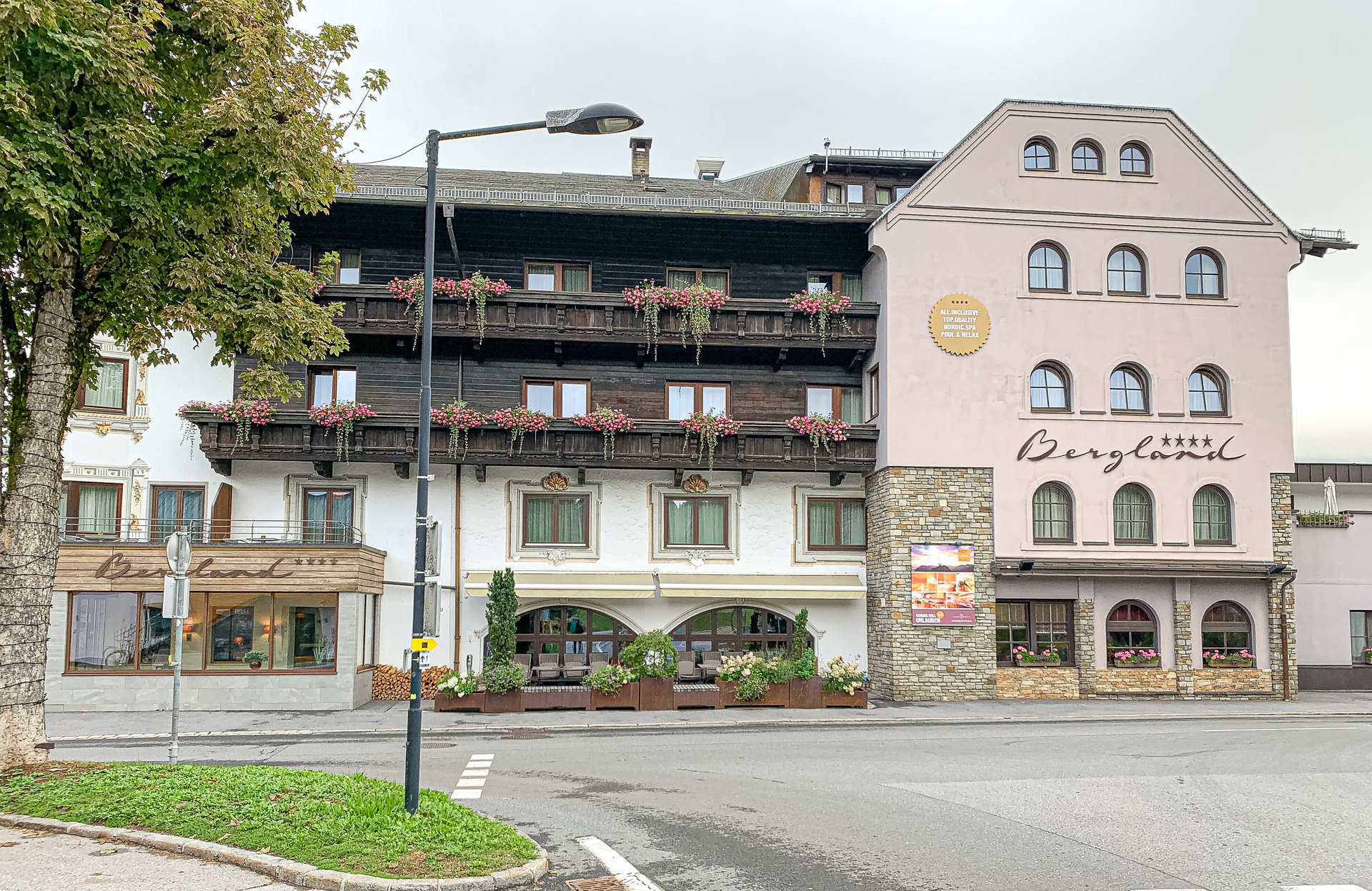 Fassade eines mehrstöckigen Hotels mit Blumenkästen an den Balkonen, Straße im Vordergrund.