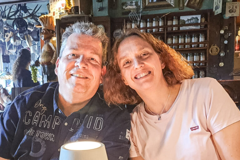 Ein Mann und eine Frau sitzen lächelnd an einem Tisch in einer gemütlichen Gaststube.