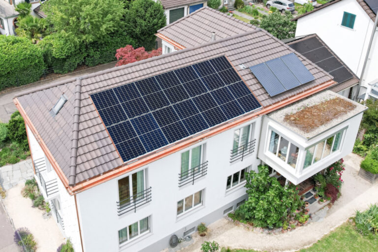 Luftaufnahme eines Hauses mit Ziegeldach, auf dem grossflächig Solarmodule montiert sind.