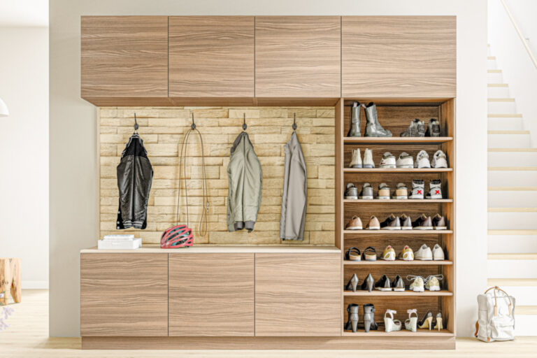 Garderobenschrank mit Hängefächern für Jacken, Schuhregal und Hakenleiste vor Steinwand.