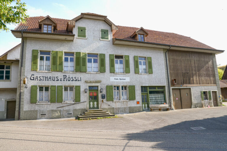 Altes verputztes Gasthaus mit grünen Fensterläden und der Aufschrift „Gasthaus z Rössli“.